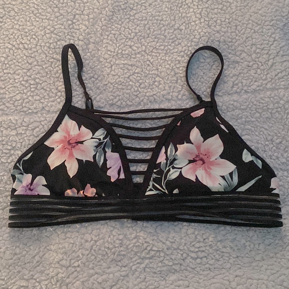 This is a detailed floral print sports bra. The bra is black, pink, and green.